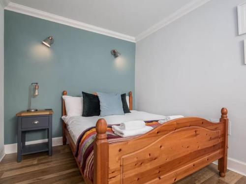 - une chambre avec un lit en bois et un mur bleu dans l'établissement The Third, à Édimbourg