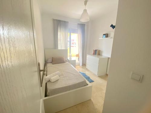 ein kleines weißes Schlafzimmer mit einem Bett und einem Fenster in der Unterkunft Fabuloso apartamento en Benalmadena con piscina in Benalmádena