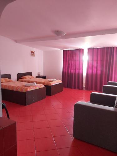 Habitación con 2 camas y suelo de baldosa roja. en La Motanu en Ghermăneşti