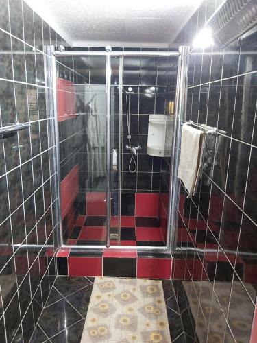y baño con ducha de azulejos rojos y negros. en La Motanu, en Ghermăneşti