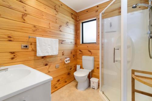 a bathroom with wooden walls and a toilet and a shower at Ngongotaha Lakeside Lodge in Ngongotaha