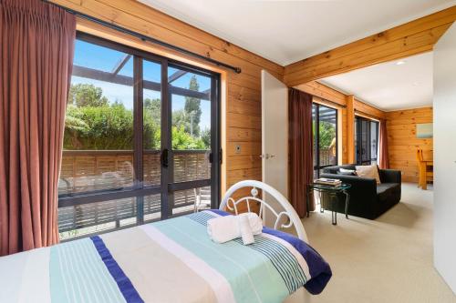 ein Schlafzimmer mit einem Bett und einem großen Fenster in der Unterkunft Ngongotaha Lakeside Lodge in Ngongotaha