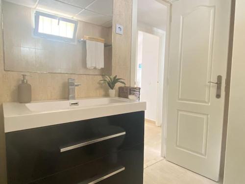 ein Badezimmer mit einem Waschbecken, einem Spiegel und einer Tür in der Unterkunft Fabuloso apartamento en Benalmadena con piscina in Benalmádena