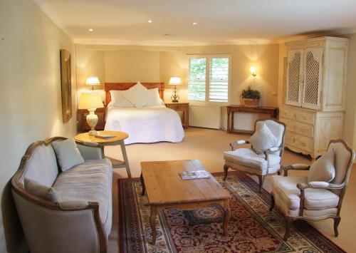 a hotel room with a bed and chairs and a table at Milton Park Country House Hotel & Spa in Bowral