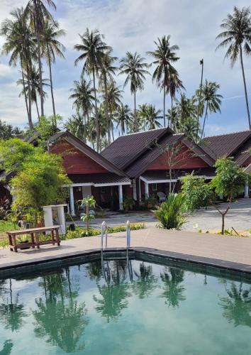 a swimming pool in front of a building with palm trees at PULANG RESORT in Setiu