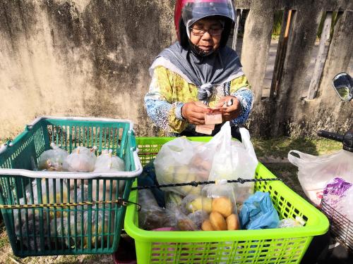 a person wearing a helmet standing next to two baskets of food at PULANG RESORT in Setiu