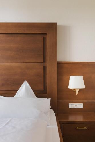 a bedroom with a bed with a wooden headboard and a lamp at Naturhotel MOLIN in San Giovanni in Val Aurina