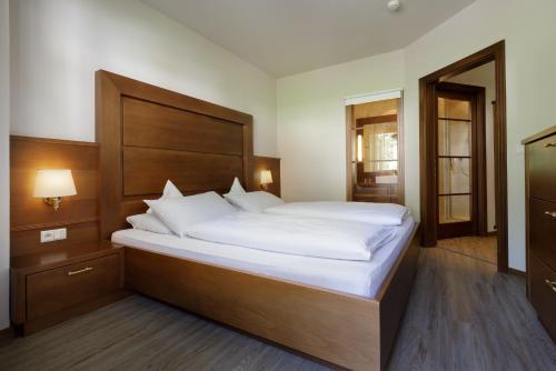 a bedroom with a large bed with white sheets at Naturhotel MOLIN in San Giovanni in Val Aurina