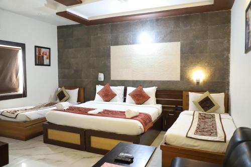 a hotel room with two beds and a table at Hotel Tara Palace by Goyal Hoteliers in Agra