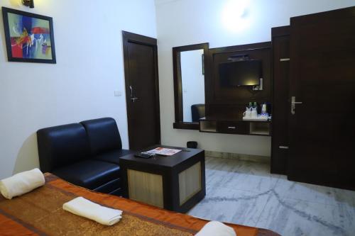 sala de estar con silla de cuero negro y TV en Hotel Tara Palace by Goyal Hoteliers, en Agra