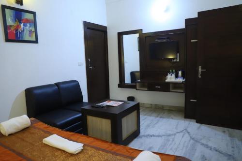 a living room with a black leather chair and a television at Hotel Tara Palace by Goyal Hoteliers in Agra