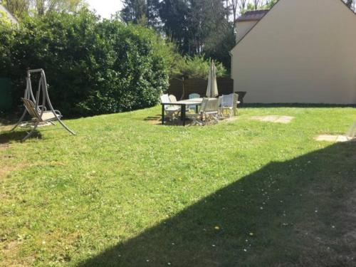 a yard with a table and chairs in the grass at Gite cosy proche Fontainebleau et foret in Noisy-sur-École