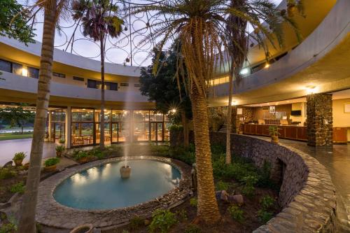 - une piscine intérieure dans un bâtiment planté de palmiers dans l'établissement Hwange Safari Lodge, à Dete