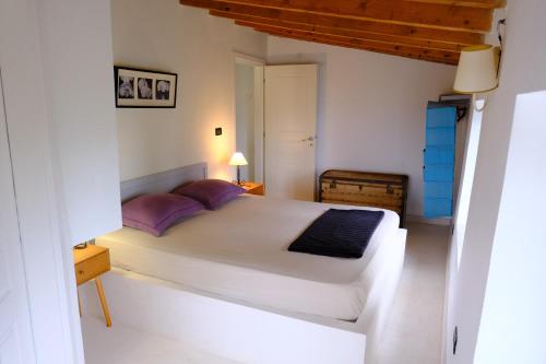 a bedroom with a large white bed with purple pillows at Les Villas de Qeparo in Qeparo