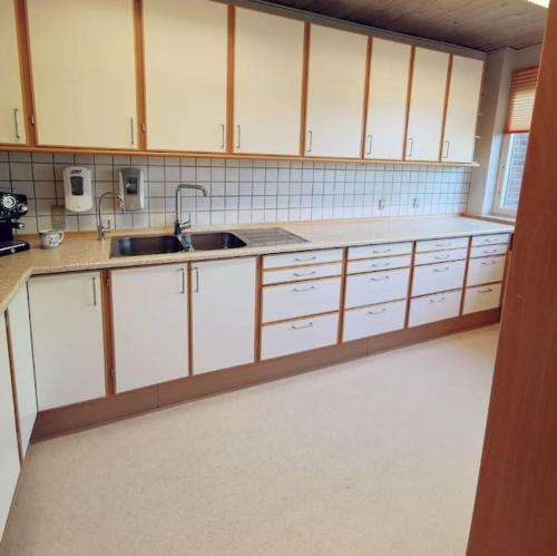 una cocina con armarios blancos y fregadero en Comfortable 3- bedroom villa with free parking en Roslev