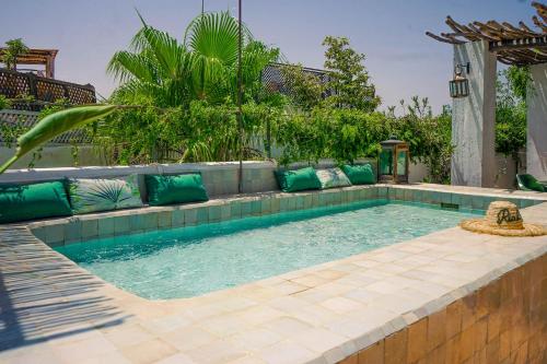 - une piscine avec des oreillers verts dans l'arrière-cour dans l'établissement Dar Titrit, à Marrakech
