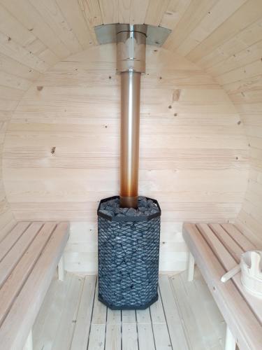 a stove in a sauna with two benches at Chalupa Les Království in Souvrať