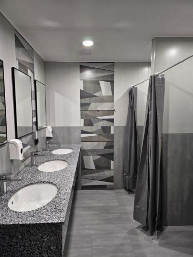 a public bathroom with three sinks and mirrors at Orion Hostel in Yerevan