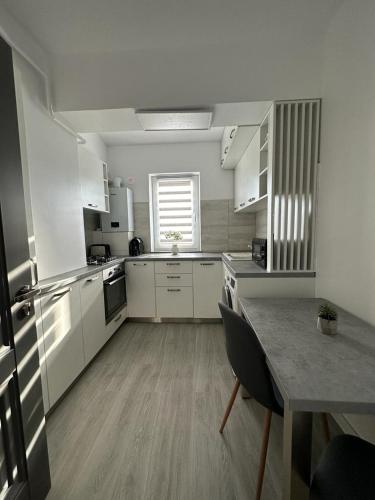 a kitchen with white cabinets and a table in it at Luxury Apartments and Studios Boulevard G Enescu Suceava in Suceava