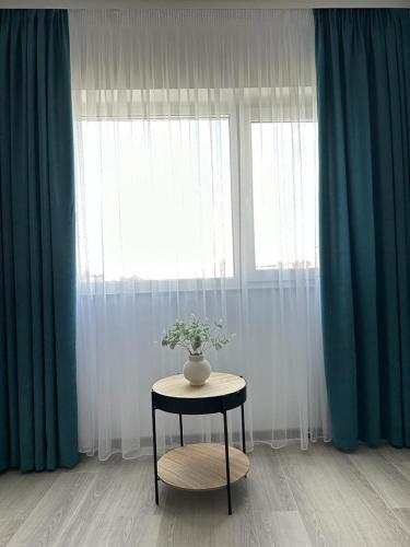 a table with a vase on it in front of a window at Luxury Apartments and Studios Boulevard G Enescu Suceava in Suceava