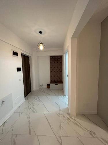 an empty living room with marble floors and a light fixture at Luxury Apartments and Studios Boulevard G Enescu Suceava in Suceava