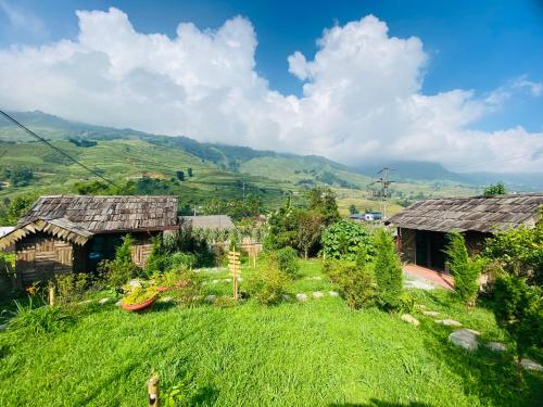 a field of grass with houses and mountains in the background at Sapa Thoc House in Sa Pa