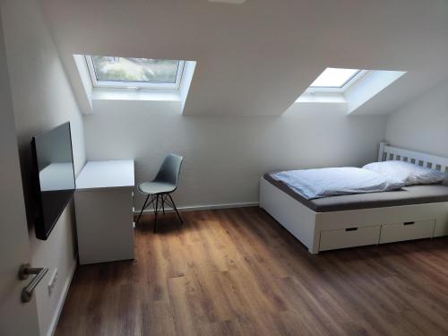 a bedroom with a bed and a desk and two windows at Apartmenthaus Pforzheim in Pforzheim