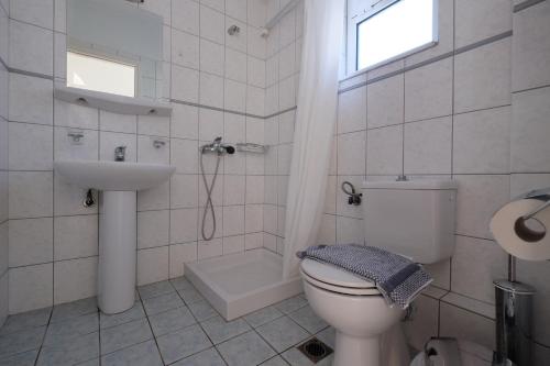 uma casa de banho branca com um WC e um lavatório em MIRSINI HOTEL em Plomari