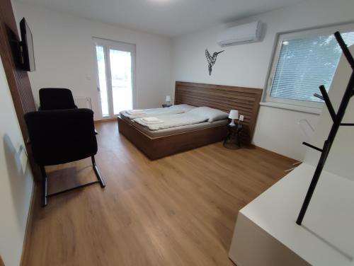 a bedroom with a bed and a chair and a window at apartmánový dom rodiny BÖJTÖS Patince in Virthova Pustatina