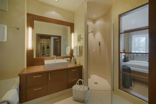 een badkamer met een wastafel, een spiegel en een bad bij Naturhotel MOLIN in San Giovanni in Val Aurina