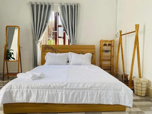 - une chambre avec un lit doté de draps blancs et une fenêtre dans l'établissement Nại Home Venuestay, à Ninh Hải