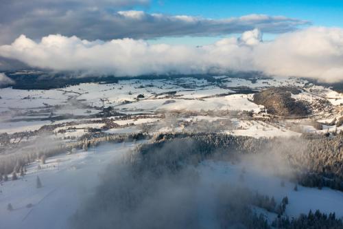 an aerial view of a snow covered valley with clouds at Azureva Métabief in Métabief