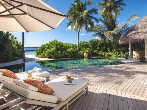 a resort with a pool and a deck with chairs and an umbrella at The Nautilus Maldives in Baa Atoll