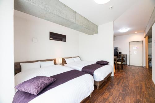2 camas en un dormitorio con paredes blancas y suelo de madera en STAYTUS - Vacation STAY 62201v en Kagoshima