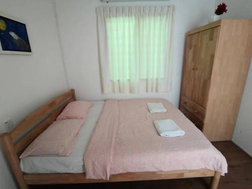 a bedroom with a bed with pink sheets and a window at Moonriver Lodge in Cameron Highlands