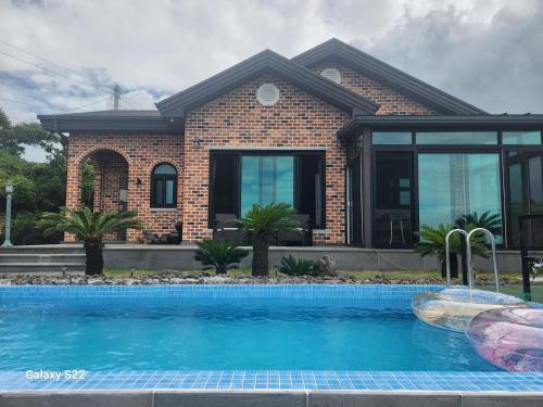 a house with a swimming pool in front of it at Sunshine Aewol Entire House in Jeju