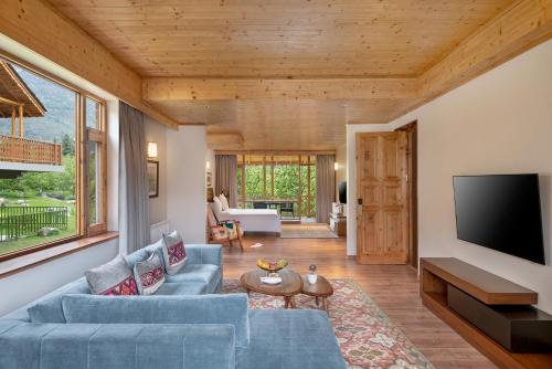 a living room with a blue couch and a tv at Welcomhotel By ITC Hotels, Hamsa Manali in Manāli