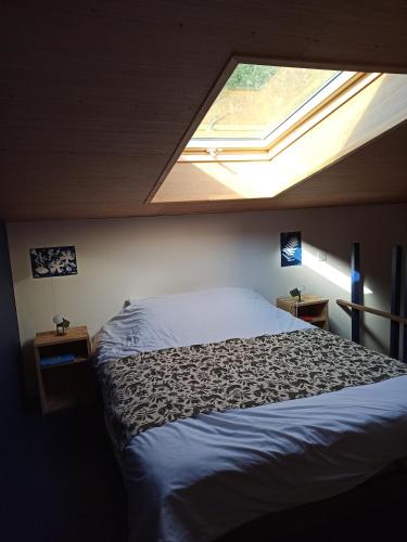 a bedroom with a large bed with a skylight at Capucine des lavandières 