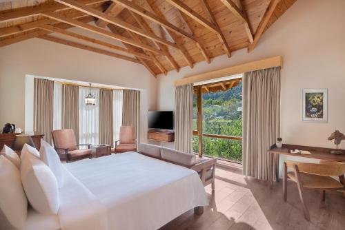 a bedroom with a large bed and a large window at Welcomhotel By ITC Hotels, Hamsa Manali in Manāli