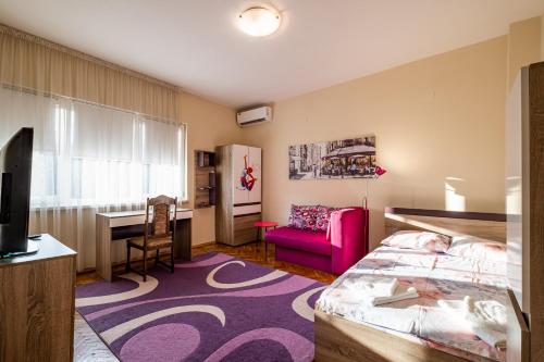 a bedroom with a bed and a desk and a tv at Primorski 2bdrm Central Apartment in Varna City