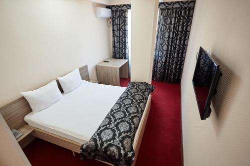 a small room with a bed and a tv at KZO Hotel in Shymkent