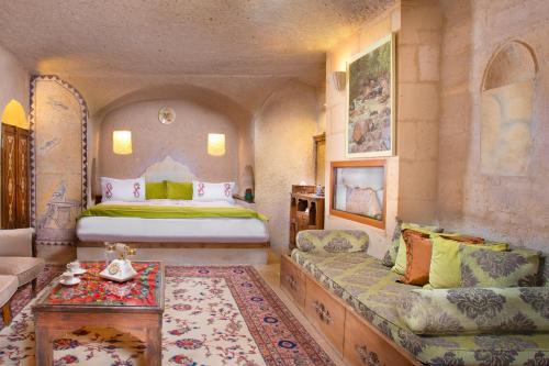 a bedroom with a bed and a couch and a table at Cappadocia Gamirasu Cave Hotel in Ayvalı