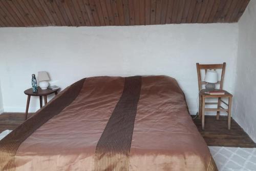 Bett in einem Zimmer mit 2 Tischen und einem Stuhl in der Unterkunft Sous les chênes – Gîte nature dans le Berry Sud in Saint-Saturnin