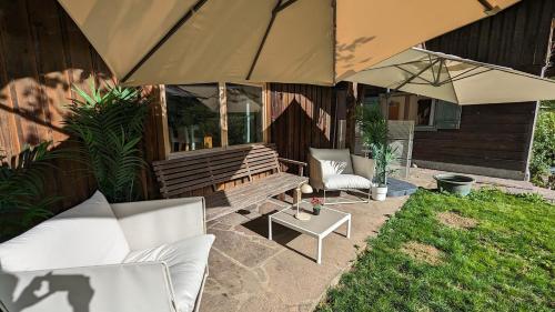 a patio with a bench and chairs and umbrellas at Gemütliches Berg-Chalet mit Panoramablick in Bayrischzell
