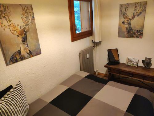 - une chambre avec un lit, une table et des peintures dans l'établissement NEW - Les Carlinottes - Méribel - Au pied des pistes - Ski In-Ski Out, à Méribel
