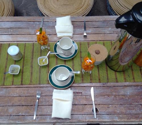 a wooden table with plates and utensils on it at Eco Tampu Andahuaylillas- Hospedaje Ecosostenible in Andalmailillas