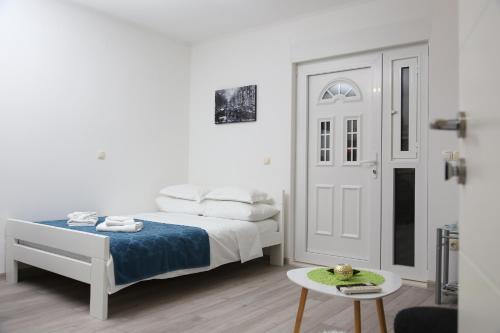 a white bedroom with a bed and a table at Studio apartman Antonio in Metković