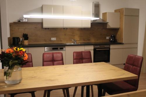 a kitchen with a wooden table with red chairs at Landhaus Eiter in Arzl im Pitztal