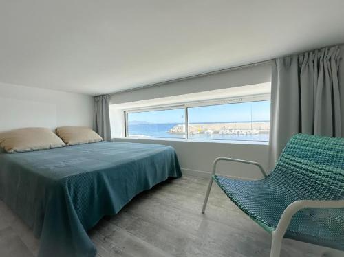 une chambre avec un lit, une chaise et une fenêtre dans l'établissement Horizon Bleu Bandol : appartement pieds dans l’eau, à Bandol
