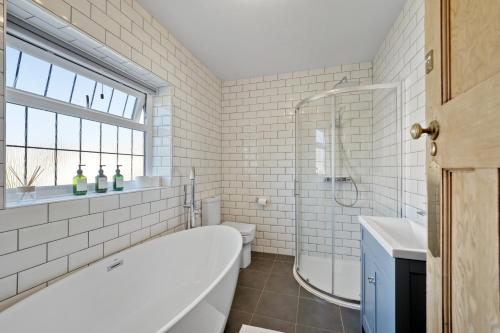 y baño blanco con bañera y ducha. en Large family house in Worthing - 5 mins from beach en Worthing